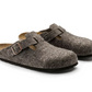 Pair of brown slippers with buckle straps on a white background