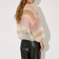 Person wearing a colorful knit sweater and black leather pants on a white background