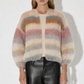 Woman wearing a multicolored sweater and black pants against a white background