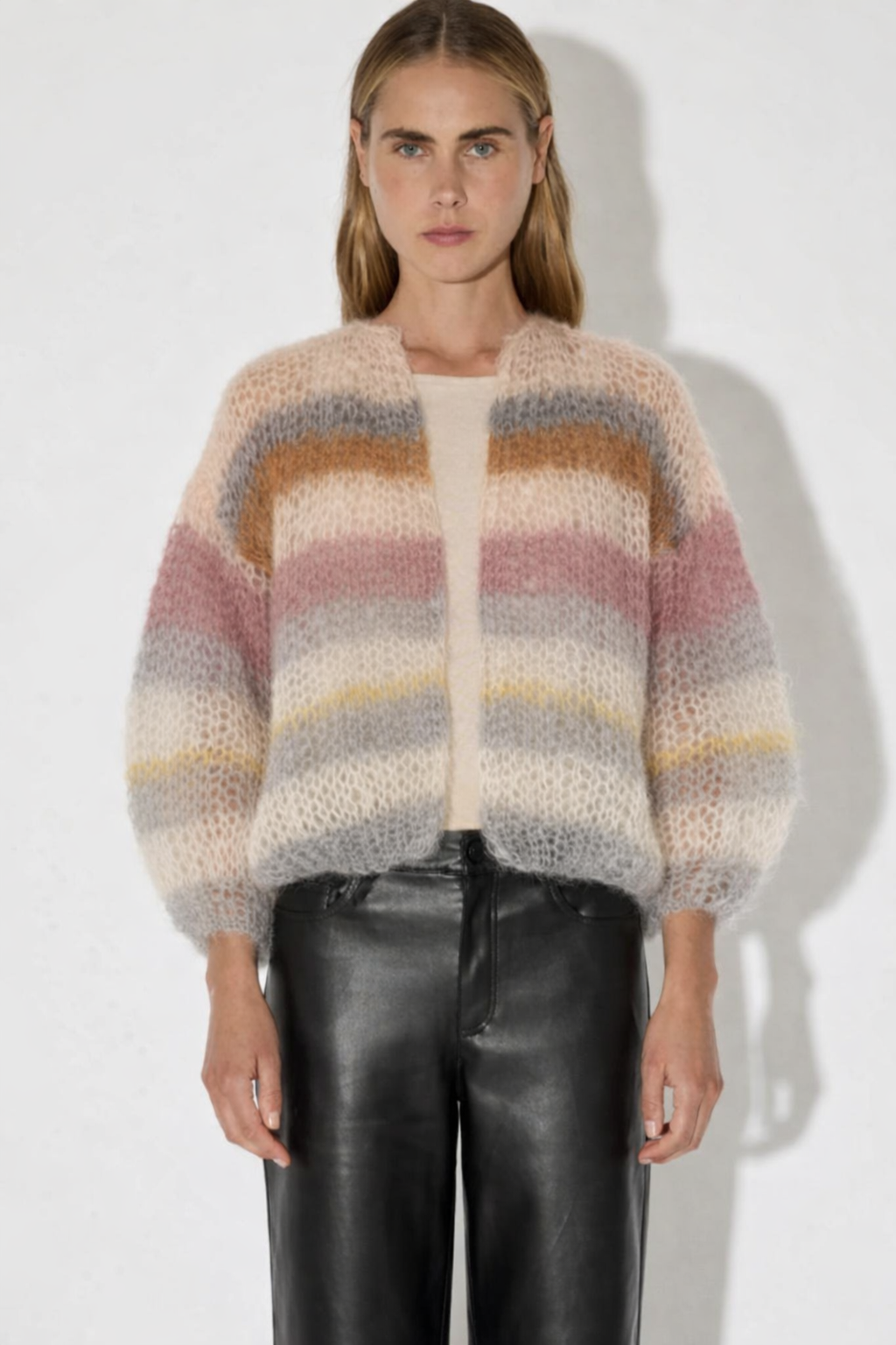 Woman wearing a multicolored sweater and black pants against a white background