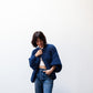 Person wearing a blue knitted sweater and jeans against a white background