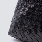 Black woven leather bag on a light gray background