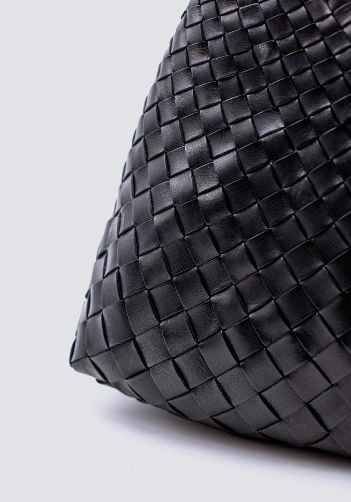 Black woven leather bag on a light gray background