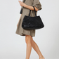 Person holding a black woven handbag against a white background