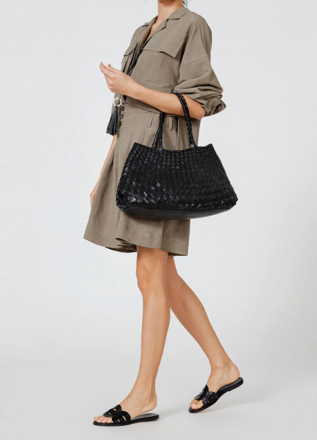 Person holding a black woven handbag against a white background