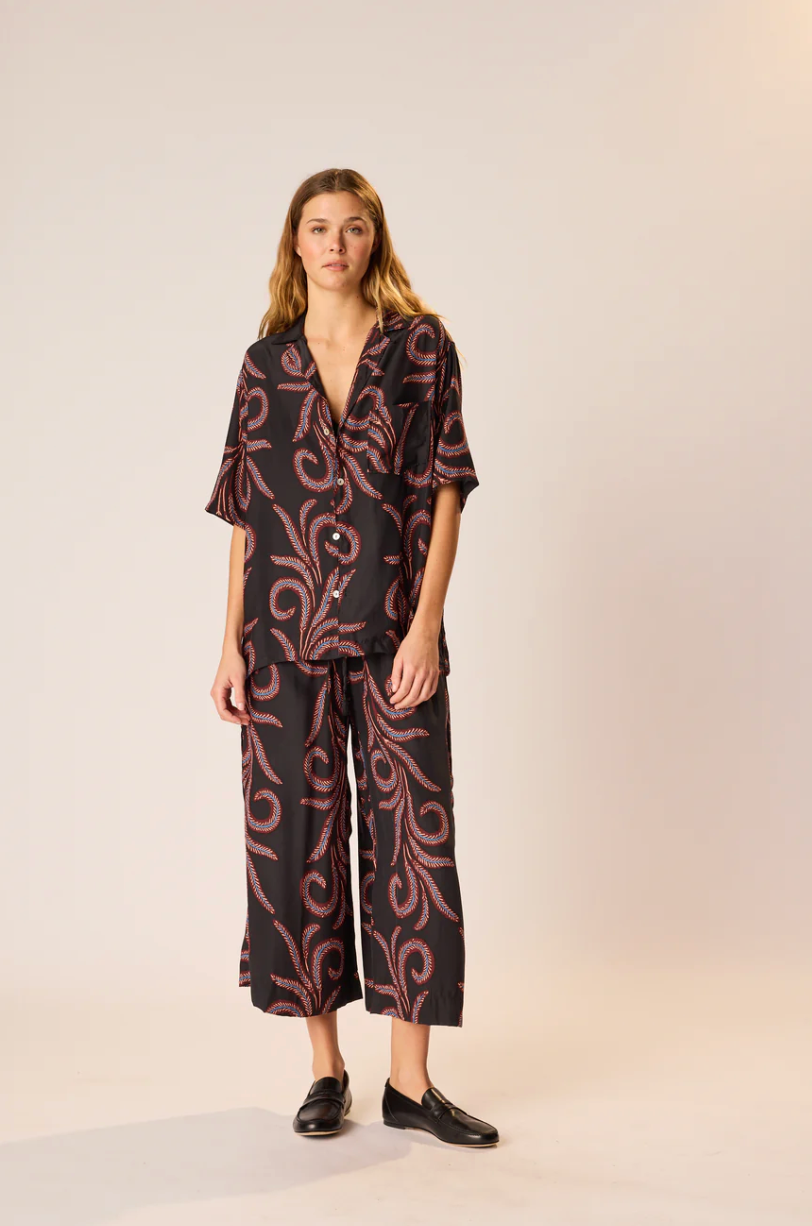 Woman wearing a black and red patterned outfit on a beige background