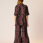 Person wearing a black and red patterned outfit on a beige background