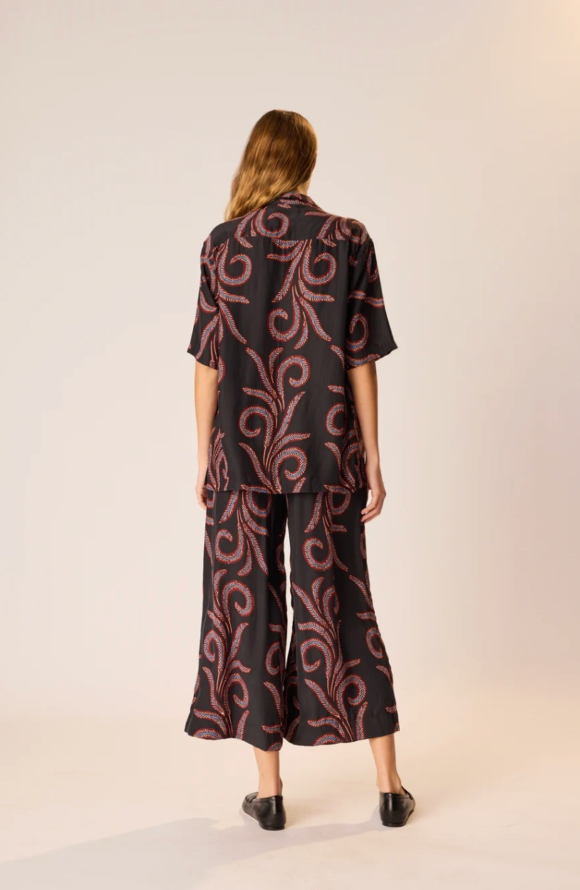 Person wearing a black and red patterned outfit on a beige background