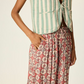Person wearing a striped vest and floral pants on a plain background