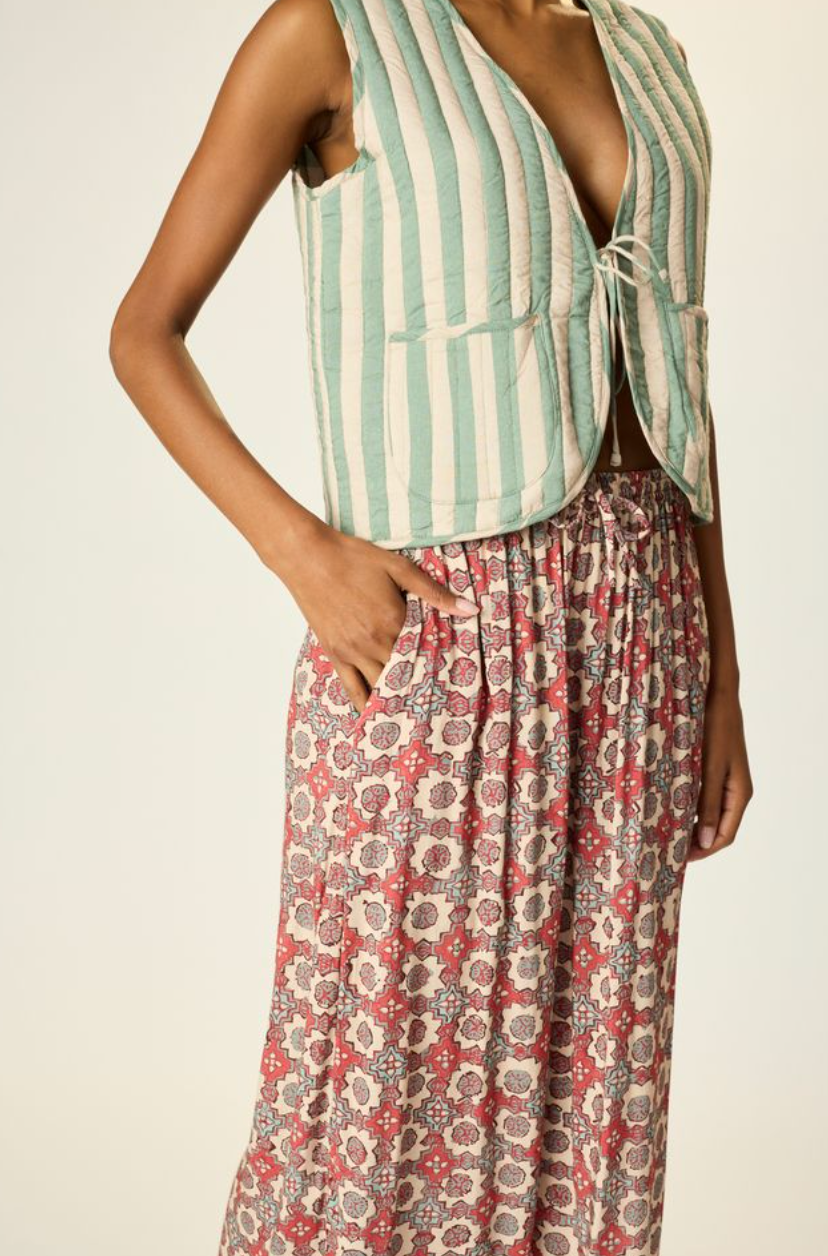 Person wearing a striped vest and floral pants on a plain background