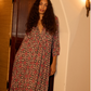 Woman wearing a patterned dress standing in a doorway.