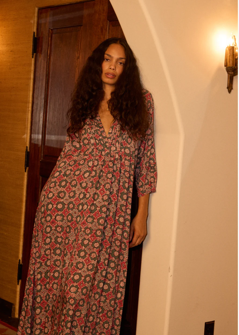 Woman wearing a patterned dress standing in a doorway.