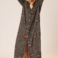 Woman wearing a black floral patterned dress on a beige background