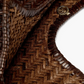 Close-up of a woven brown leather product with a brand logo.