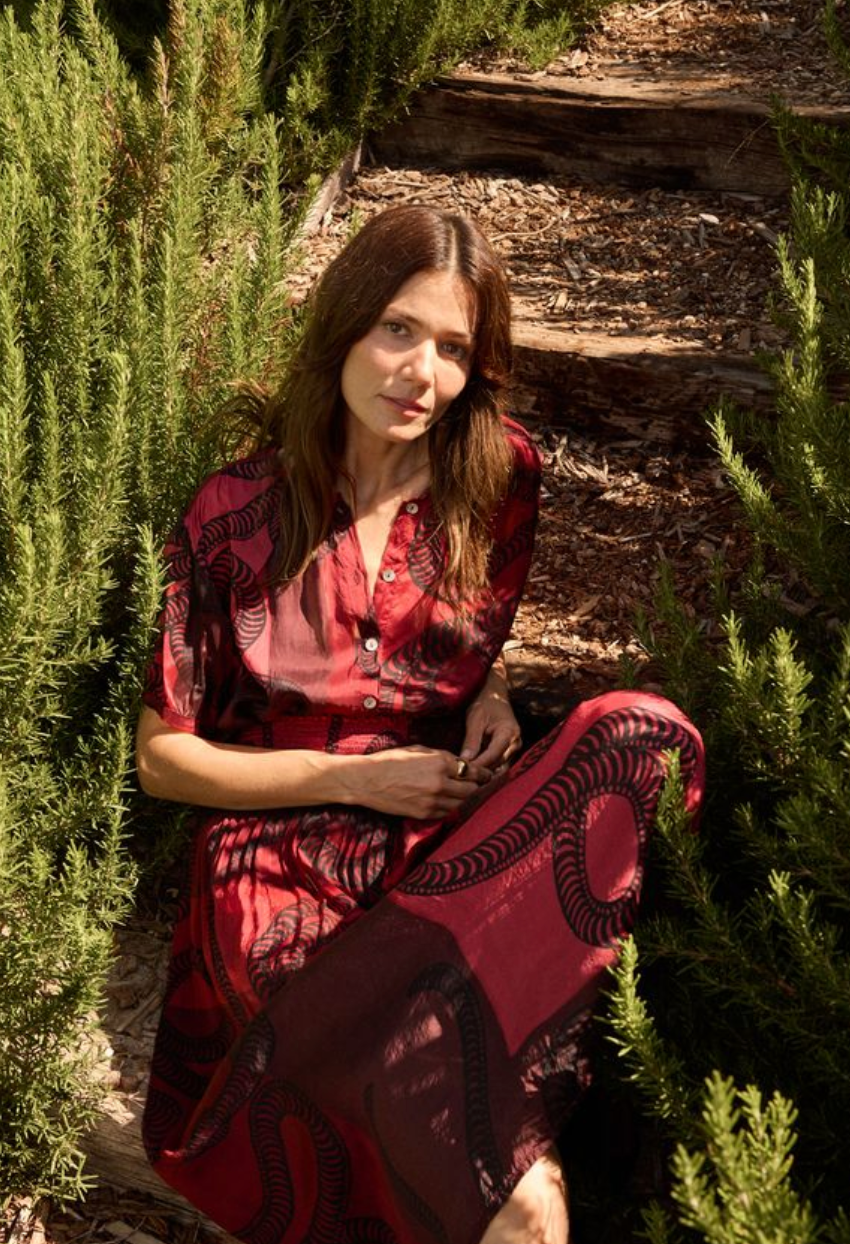 Woman in a red dress sitting among green plants
