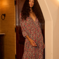 Woman in a floral dress standing in a doorway with warm lighting. dress is 100% rayon 