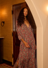 Woman in a floral dress standing in a doorway with warm lighting. dress is 100% rayon 