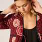 Woman wearing a red floral kimono against a plain background