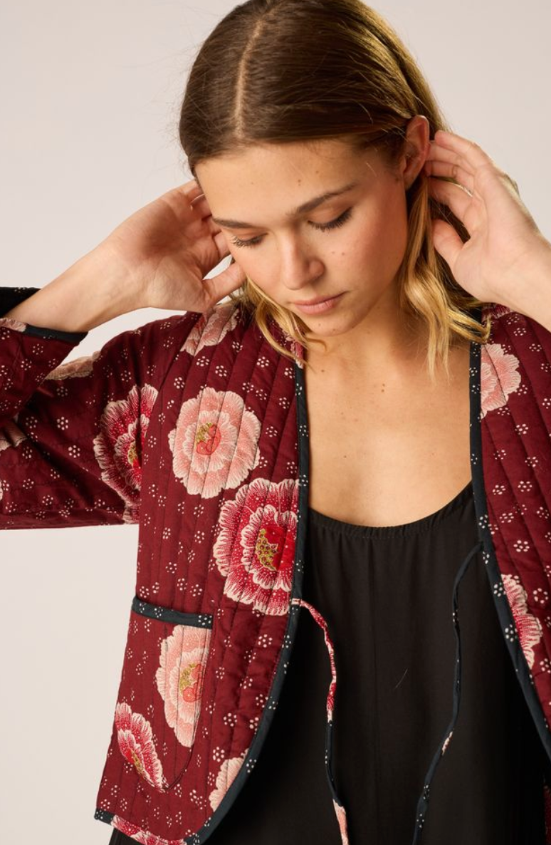 Woman wearing a red floral kimono against a plain background