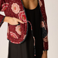 Person wearing a floral patterned jacket over a black outfit on a white background