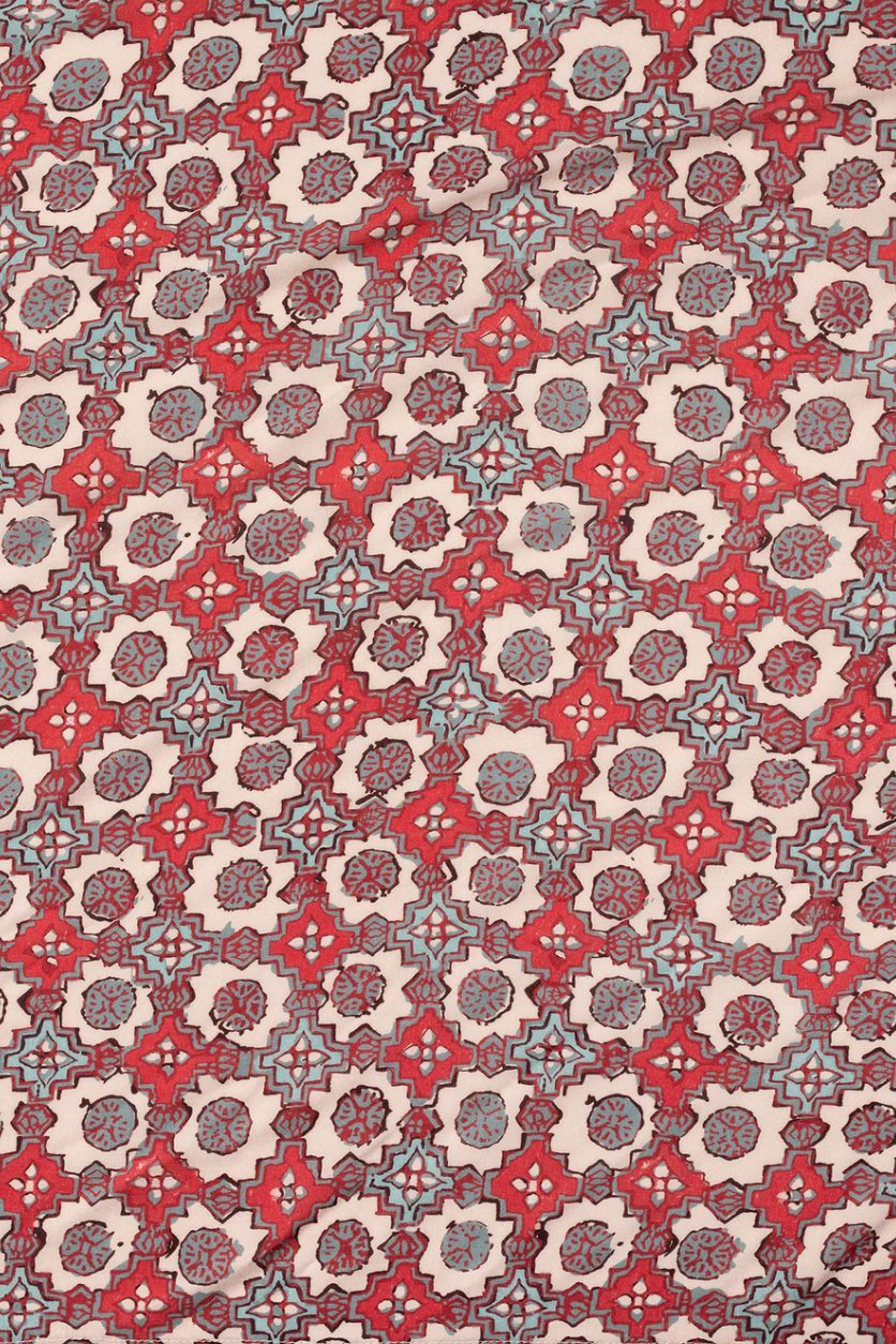 Patterned fabric with red, blue, and beige colors on a beige background
