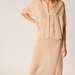 Woman wearing a beige polka dot dress on a plain background