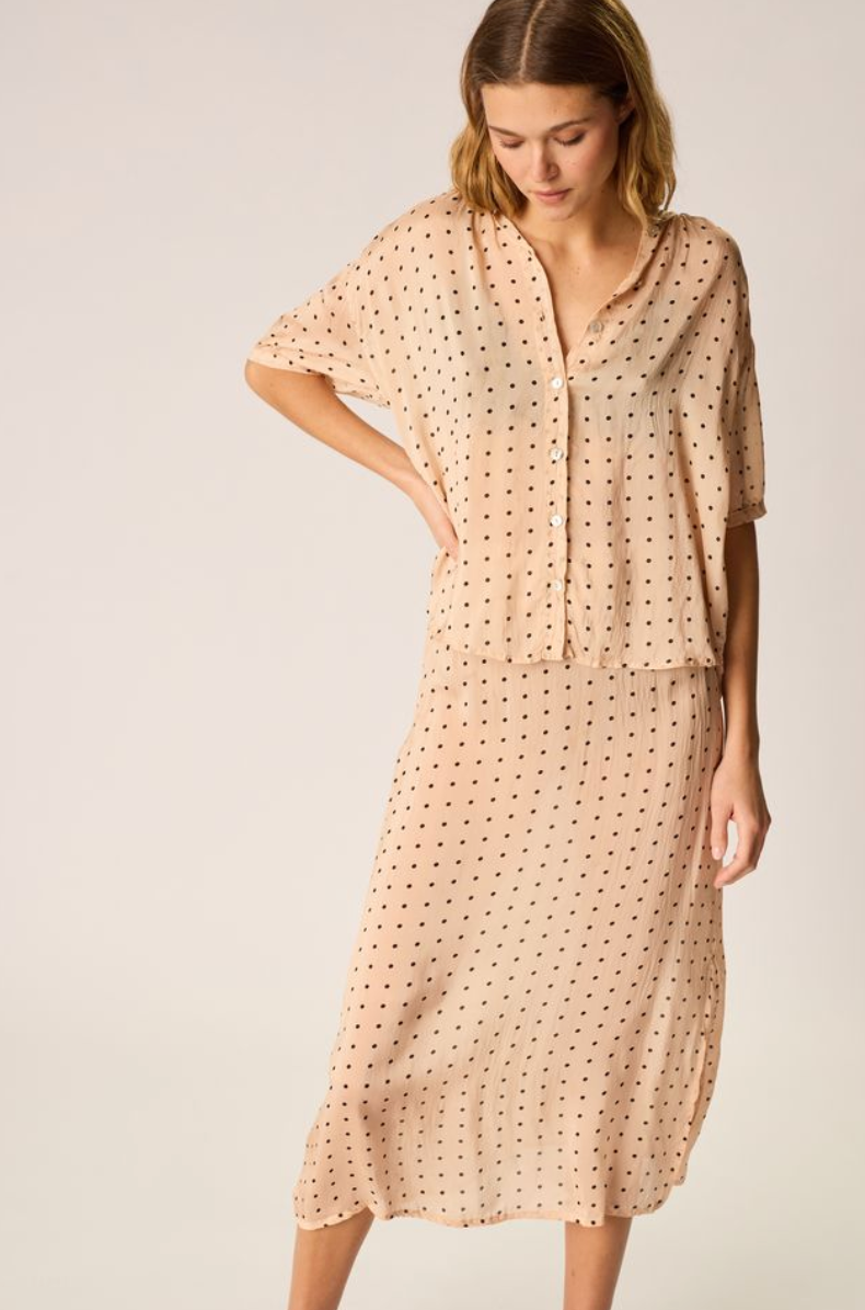 Woman wearing a beige polka dot dress on a plain background